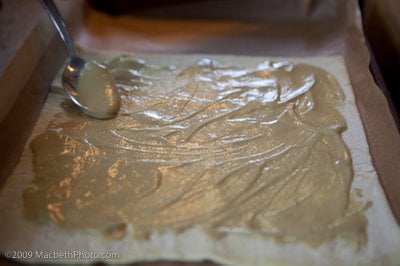 Spreading mustard on puffed pastry sheet