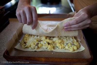 Laying second puffed pastry sheet on top of eggs and cheese to make it into a giant egg sandwich.