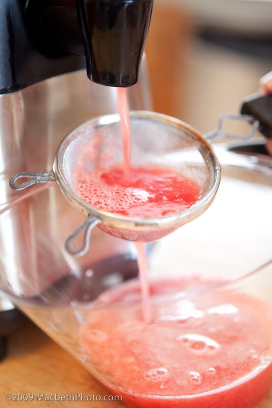 Straining first blend of watermelon juice through sieve to remove pulp and seeds.