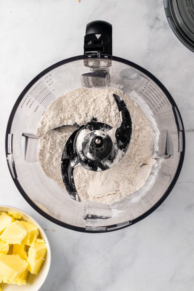 Overhead view of dry ingredients in a food processor before pulsing.