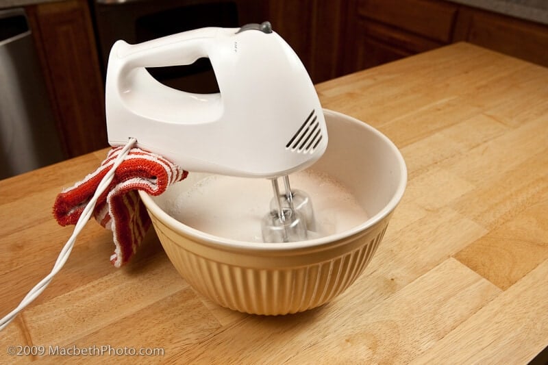 hand mixer balanced on large mixing bowl with a folded kitchen towel