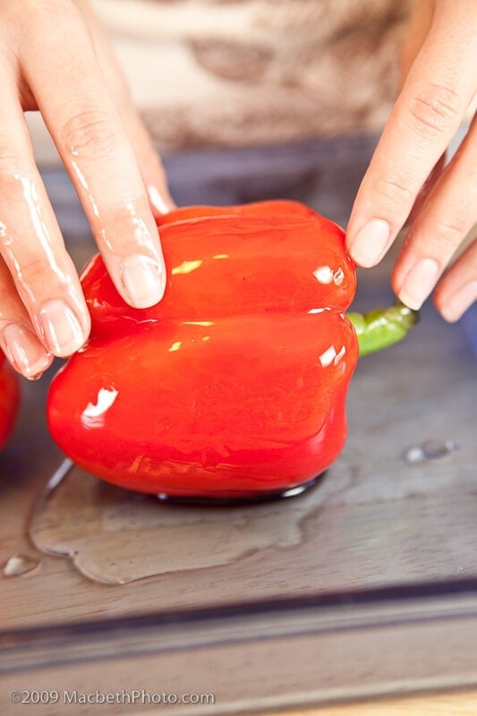 Coating red peppers in olive oil.