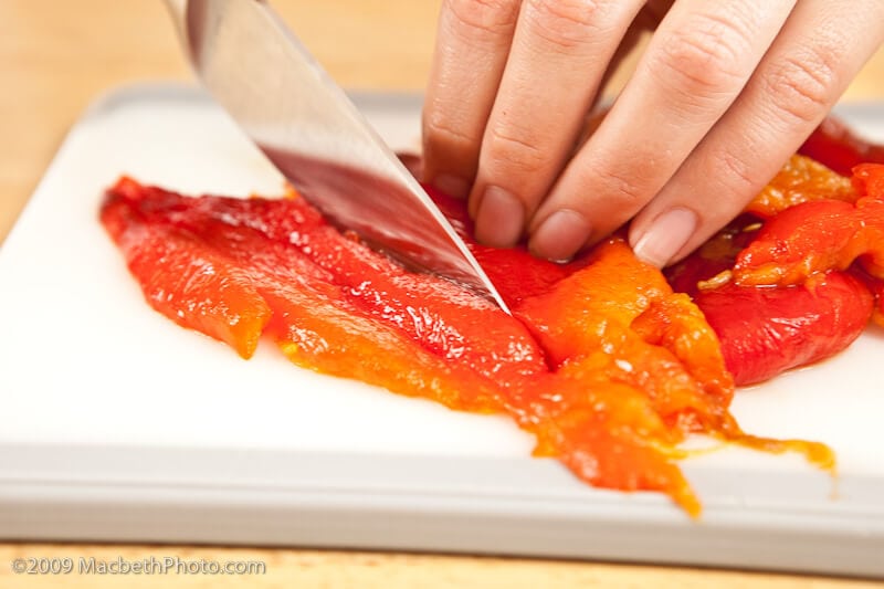 Slicing roasted red peppers into strips for recipe.