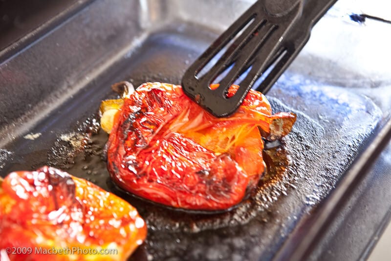 Charred red peppers after being baked for 45 minutes. They look browned on the skin and have deflated in size.