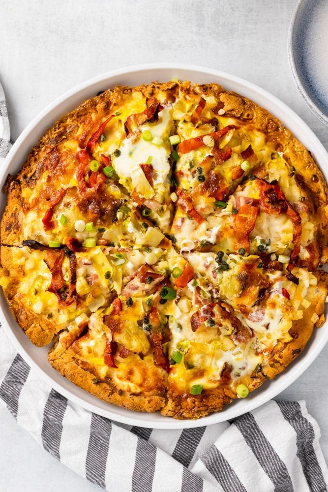 Overhead look of baked breakfast pizza in a deep white dish.