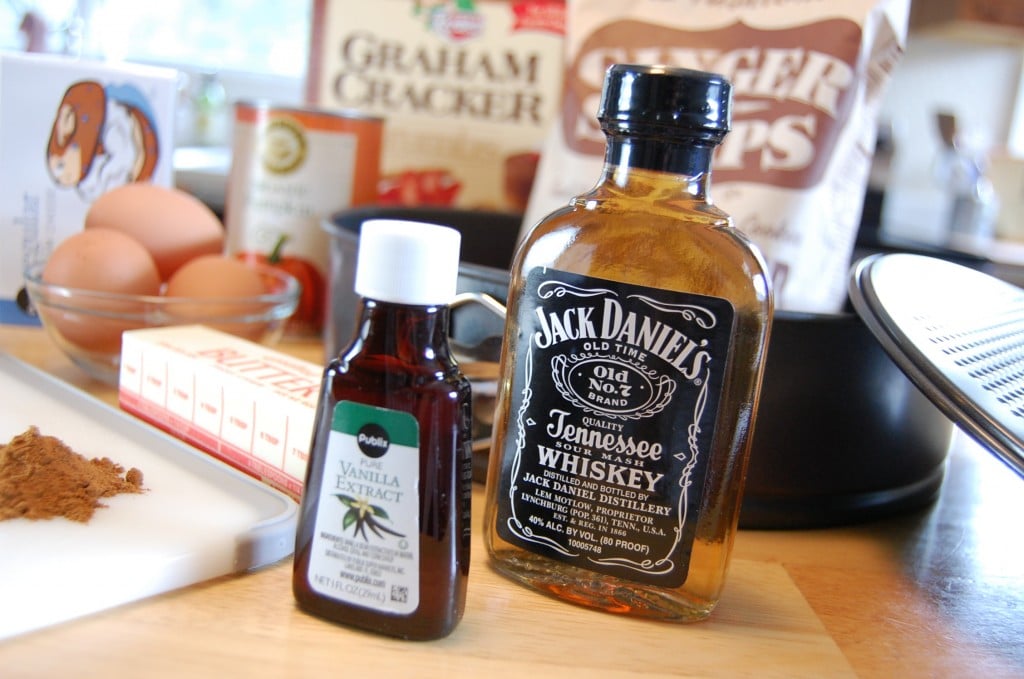 Ingredients for pumpkin cheesecake on a counter, with Jack Daniel's whiskey highlighted in the center.