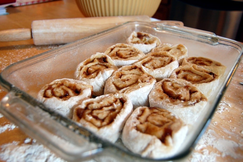 Cut homemade cinnamon rolls laid out into a glass baking pan.
