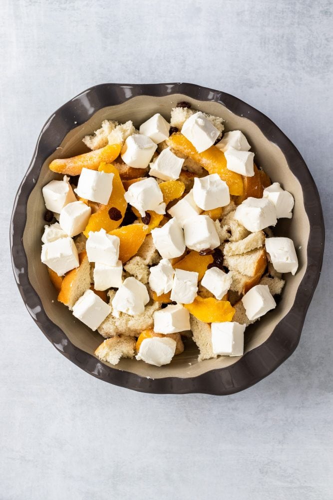 Overhead shot showing cubes of cream cheese on top of bread and peaches.