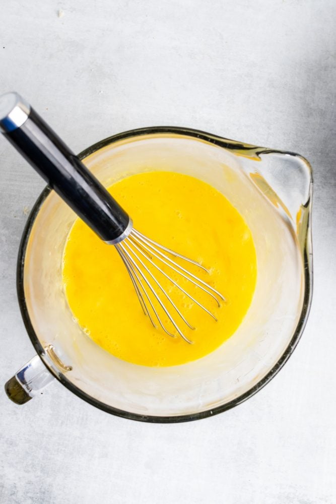 Overhead shot of whisking eggs in a measuring bowl.