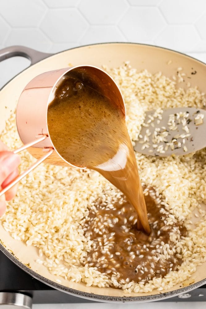 Pouring the broth with melted brie into the rice.