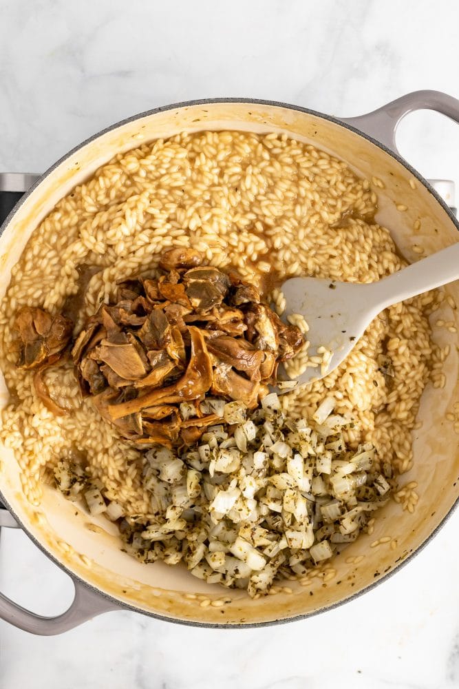 Adding the mushrooms and onions back to the risotto.