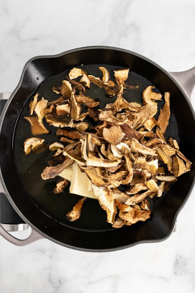 Adding dried mushrooms to sauté pan.