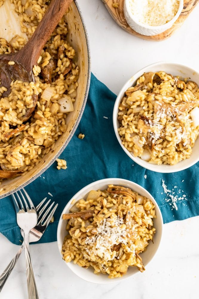 Serving two bowls of Champagne risotto with Parmesan cheese sprinkled on top.