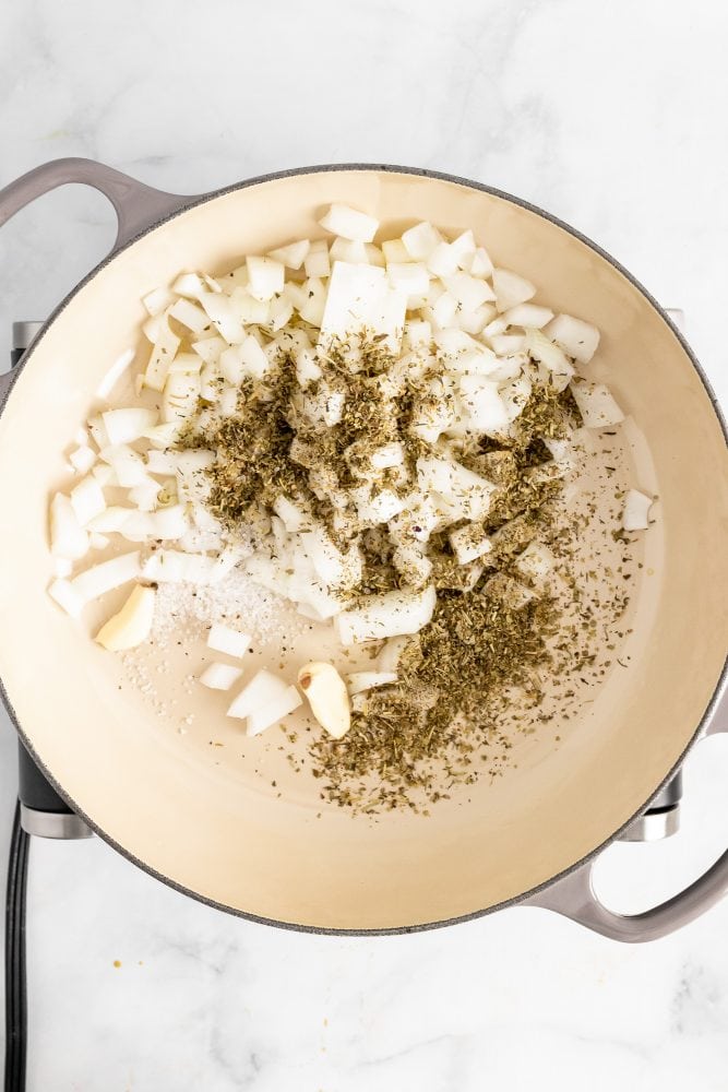 Adding onions, spices, and garlics into large pot to sauté.