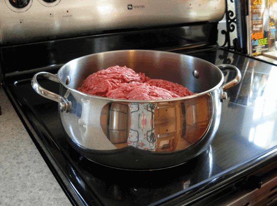 Raw ground beef and pork in a large stainless steel pot.