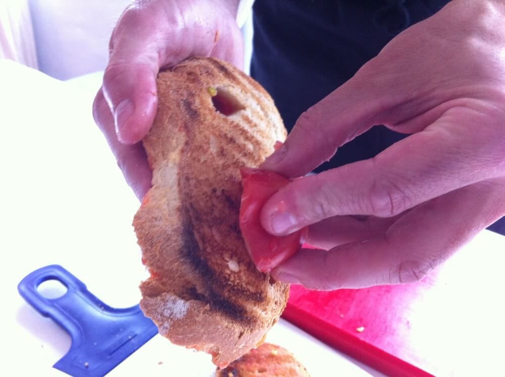 Cooking class in Spain showing how to make pa amb tomaquet, Spanish tomato bread.