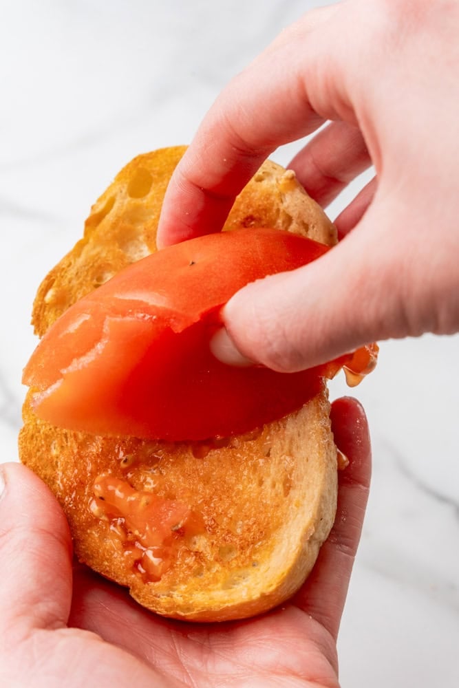 Rubbing tomato on toasted bread.