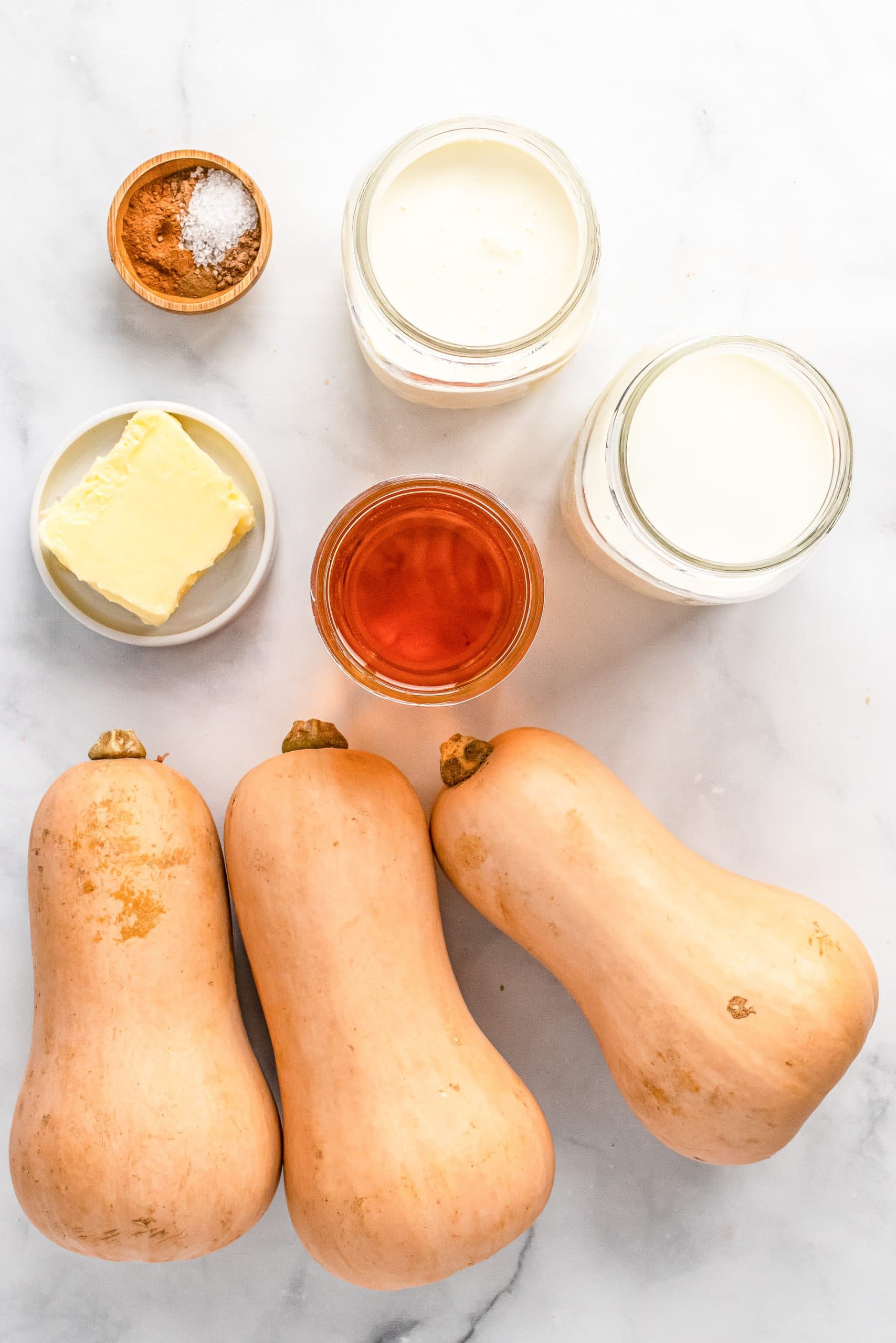 Overhead view of ingredients for roasted butternut squash soup including spices, milk, cream, apple juice, butter, butternut squash.