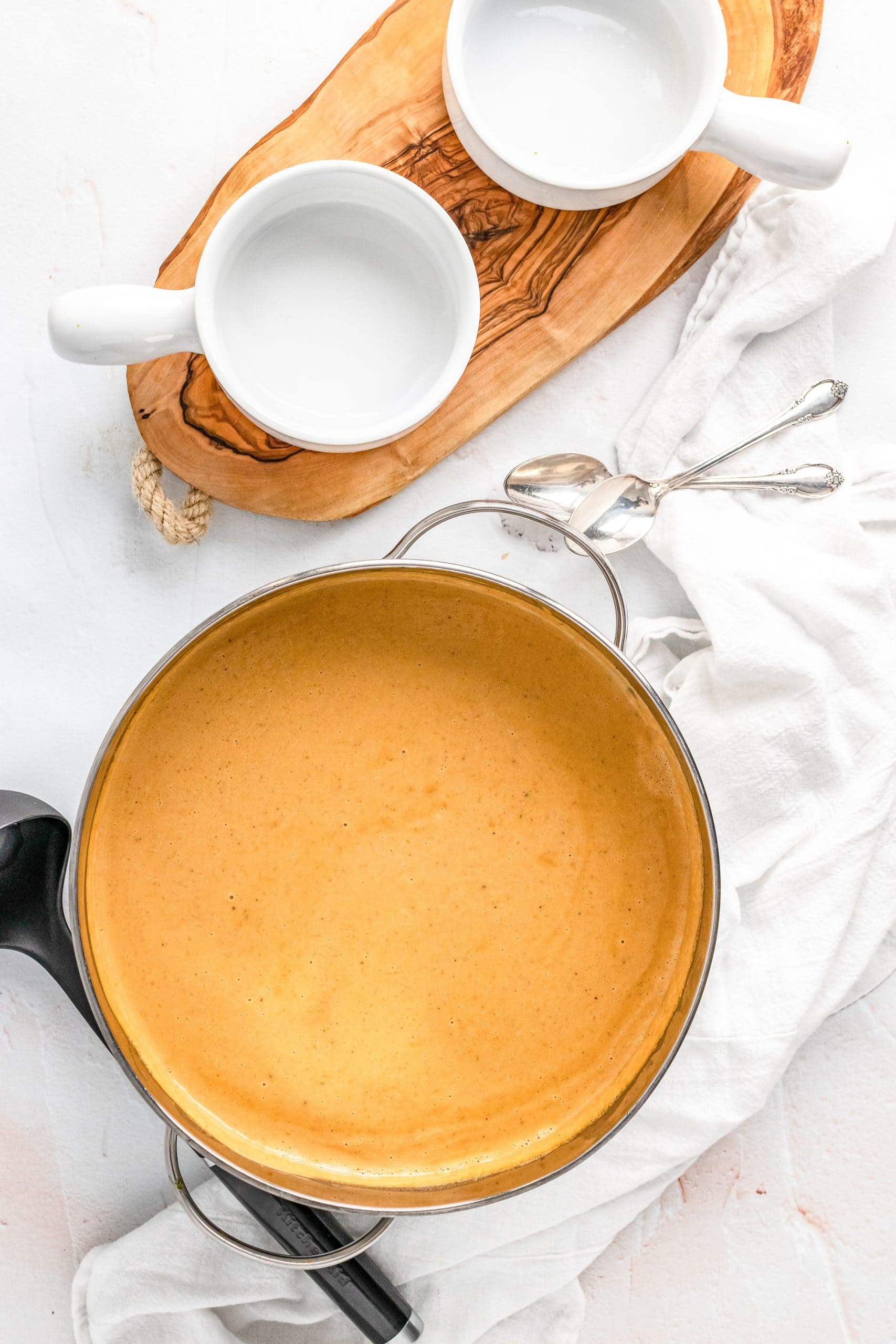 Overhead shot of pot of soup with two small white bowls for serving.