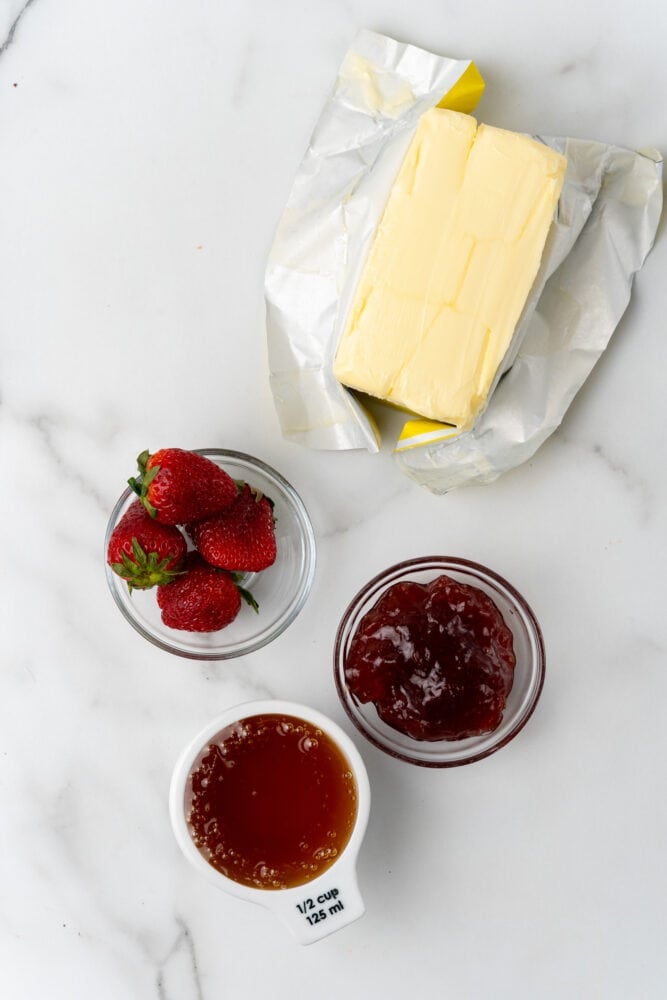 Ingredients for whipped strawberry butter including butter, strawberries, honey, and strawberry preserves