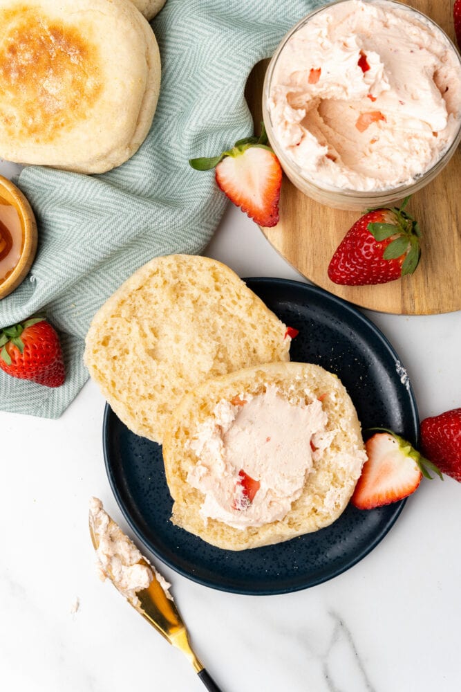 overhead shot of a breakfast spread including fresh strawberries, a blue chevron towel, English muffin with strawberry honey butter 