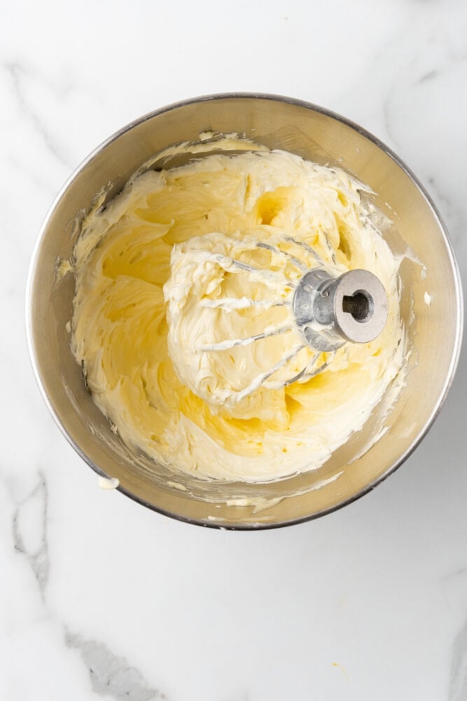 whipped butter in the bowl of a stand mixer with whisk attachment inside