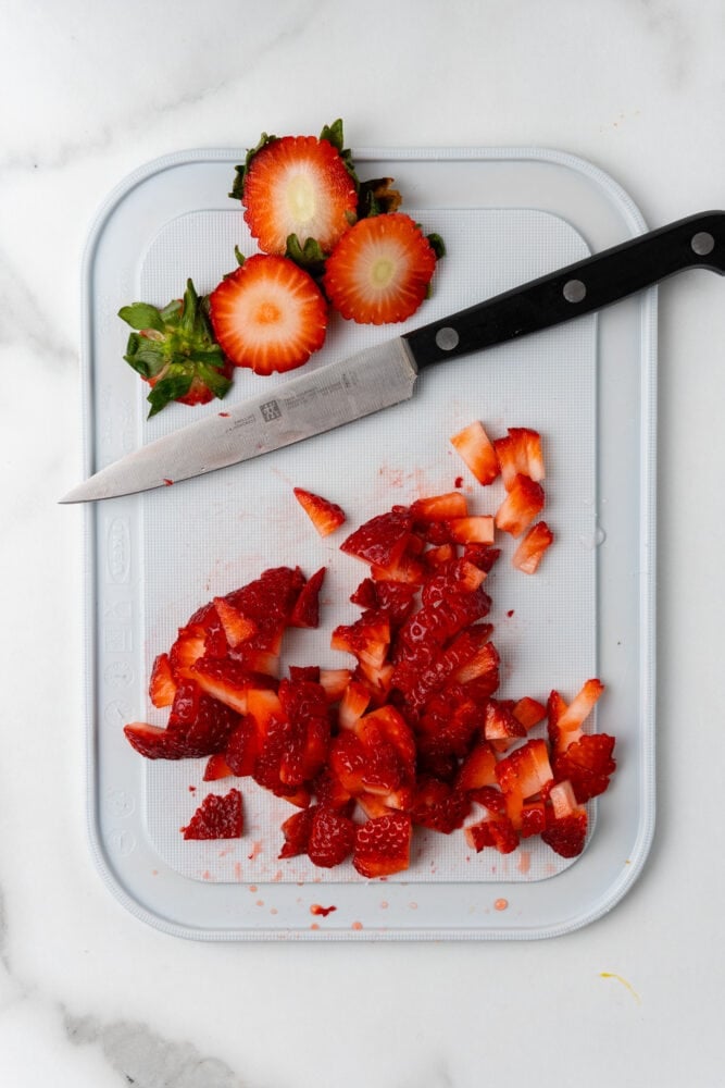 sliced strawberries on a white cutting board