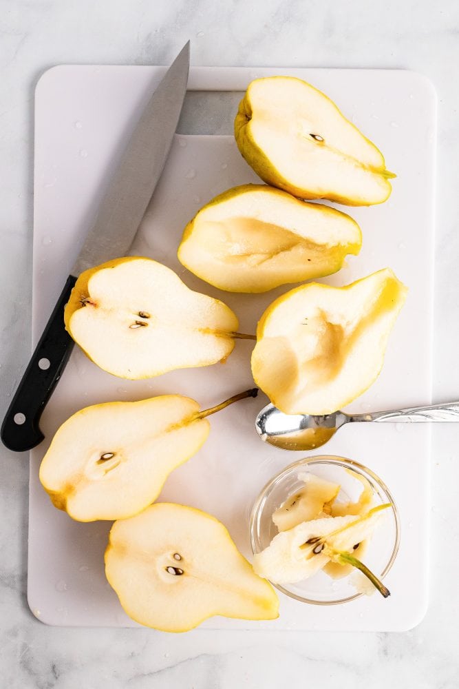 Slicing and coring pears on a white cutting board.