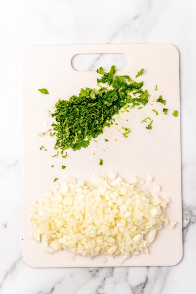 chopped cilantro and onion on a white cutitng board