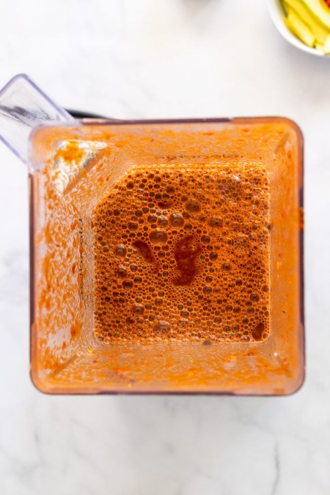Overhead shot of the sauce ingredients mixed in a blender with a rich, orange/red color.