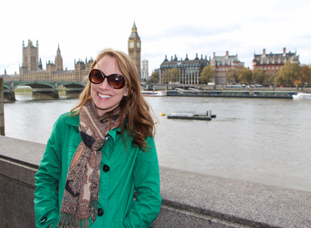 Rachelle in a green jacket wearing sunglasses and standing in front of Big Ben