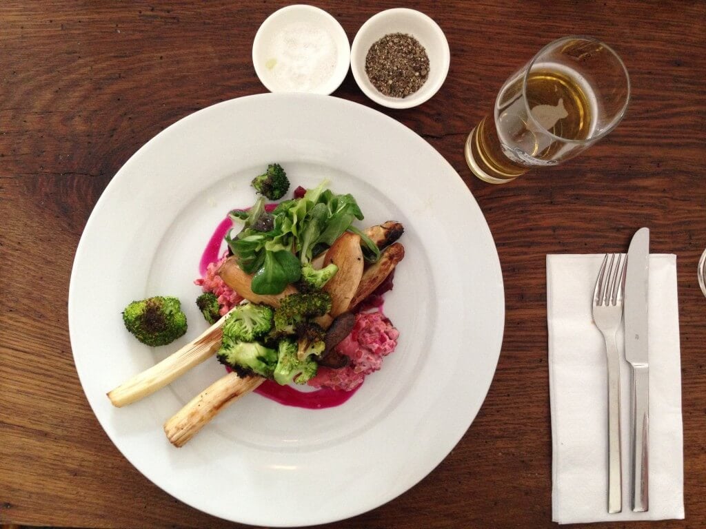 Overhead shot of spelt risotto, colored pink with beet juice and topped with roasted vegetables.