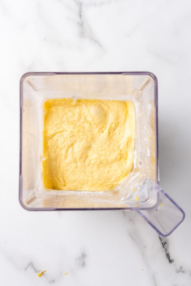 Lemon ricotta pancake batter blended in a blender. It's light yellow in color and a little lumpy in texture.