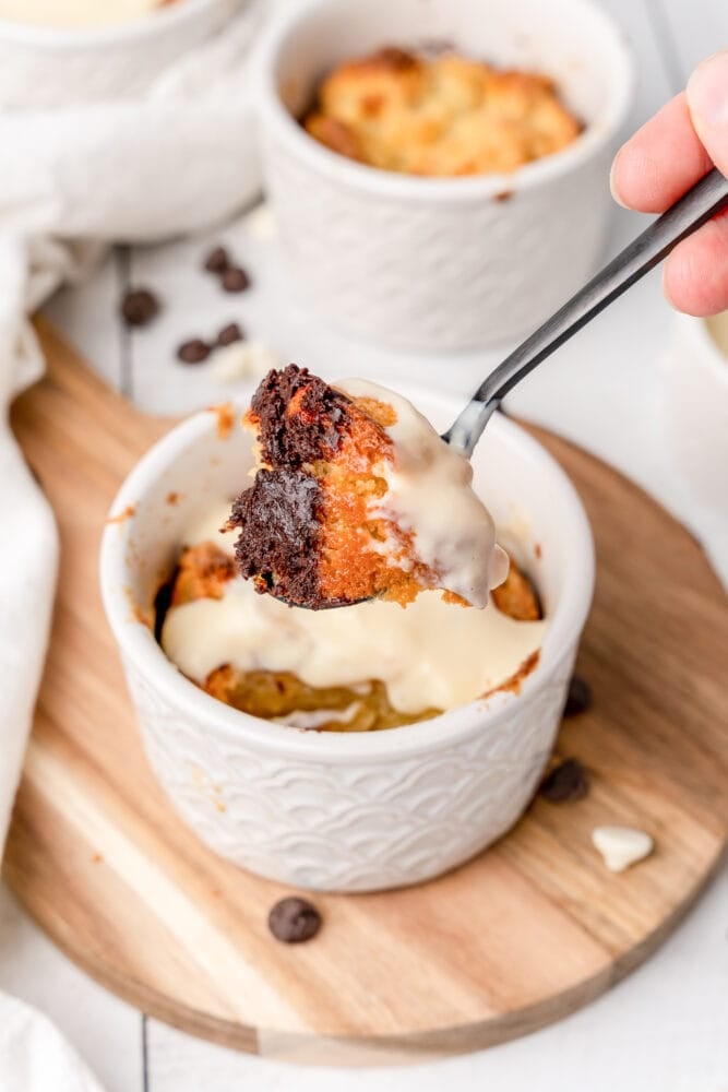white chocolate bread pudding in a white ramekin with a spoon full lifted for a bite