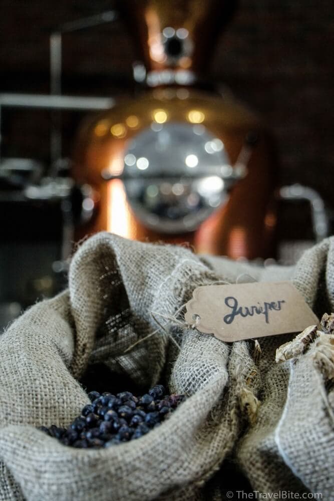 A sack of juniper berries sitting next to a copper pot still.