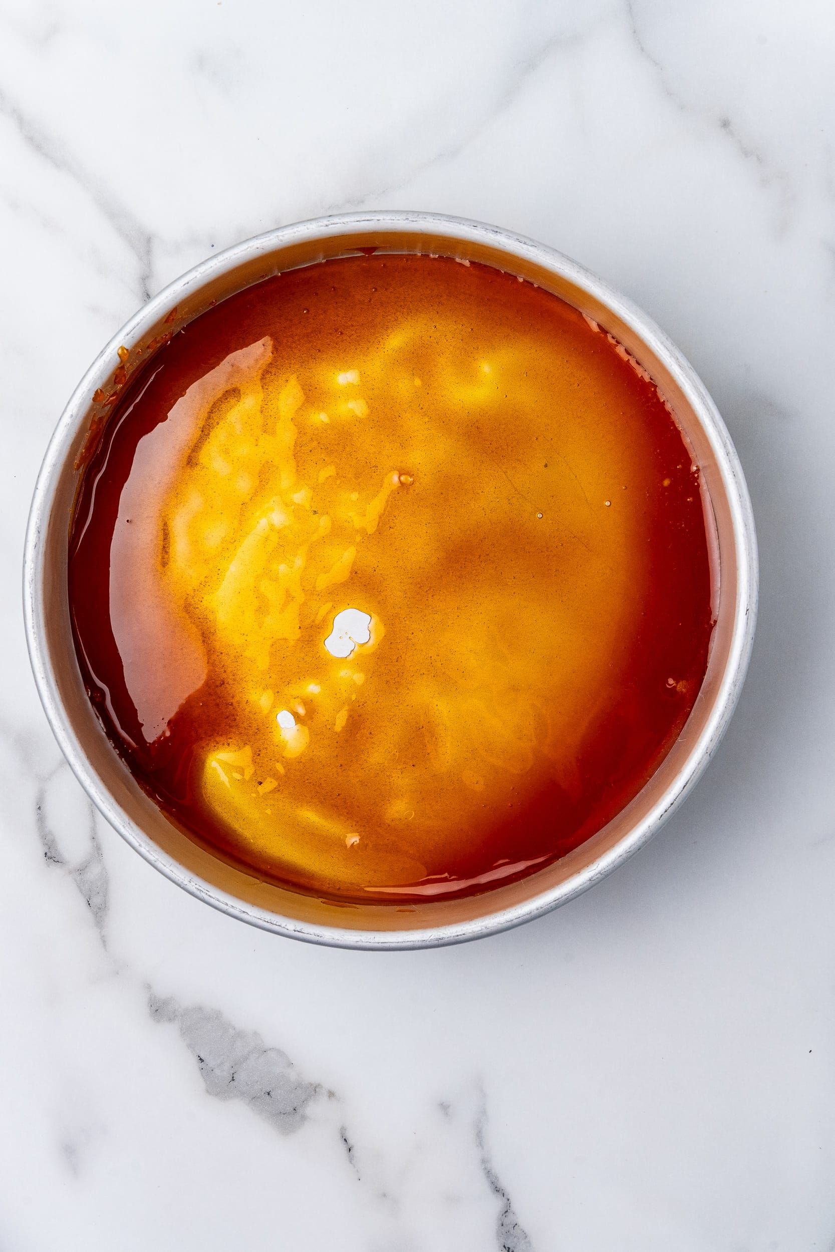 Caramelized sugar poured into a round cake pan.