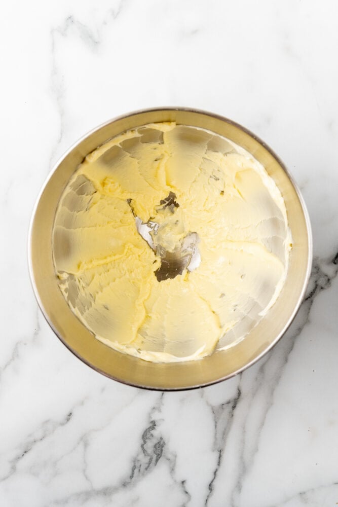 Softened butter creamed in a large stainless steel bowl.