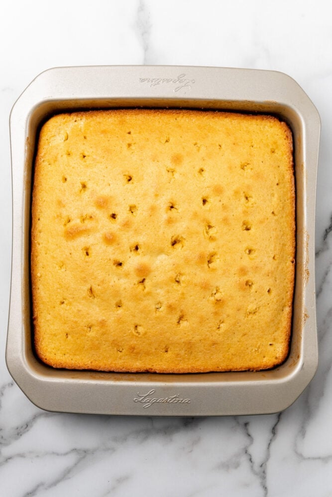 baked tres leches cake with holes punched in to add the milk mixture