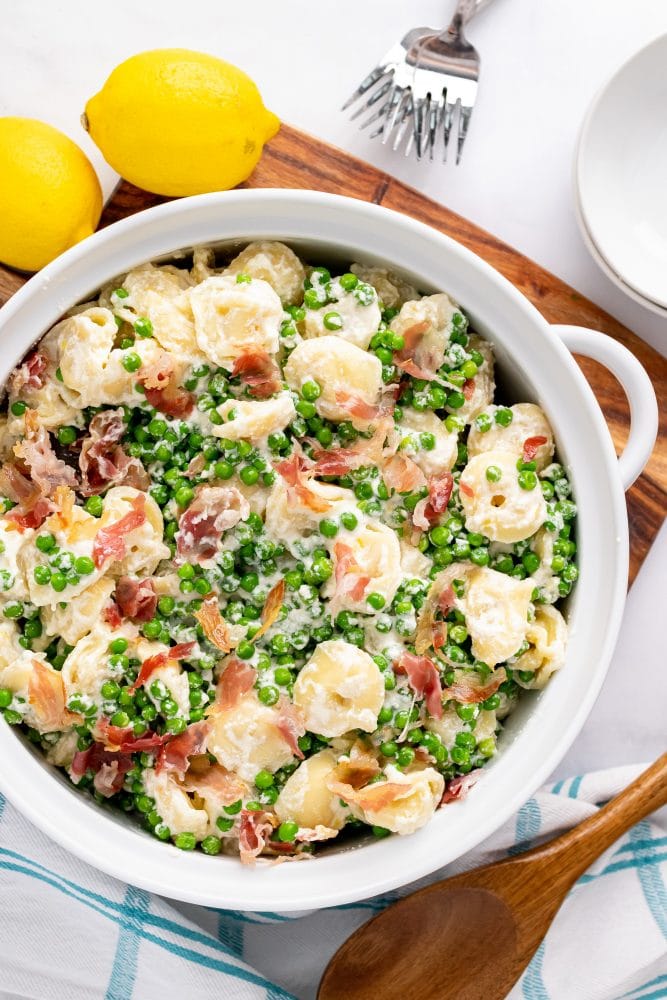 Overhead shot of one large serving bowl filled with lemon pasta with pancetta and peas.