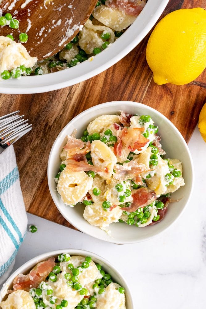 Overhead shot of two bowls filled with lemon pasta with pancetta and peas.