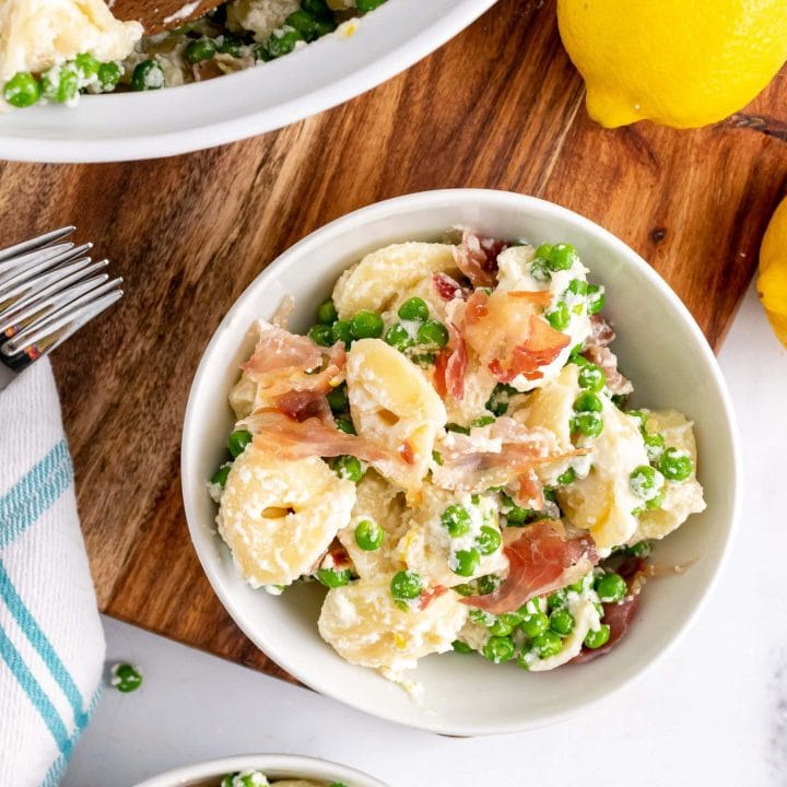 Overhead shot of two bowls filled with lemon pasta with pancetta and peas.