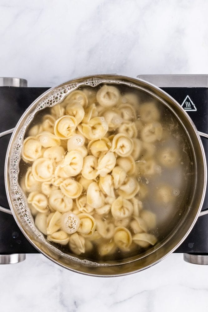 Overhead look at a pot of boiling water filled with tortellini.