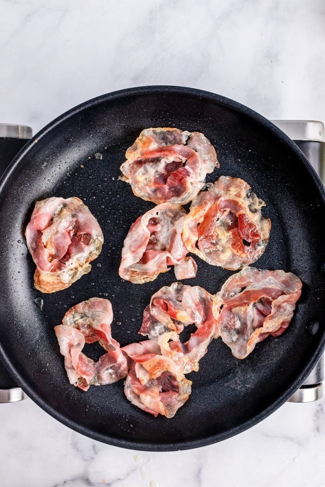 Overhead look at crispy cooked pancetta in a non stick skillet.