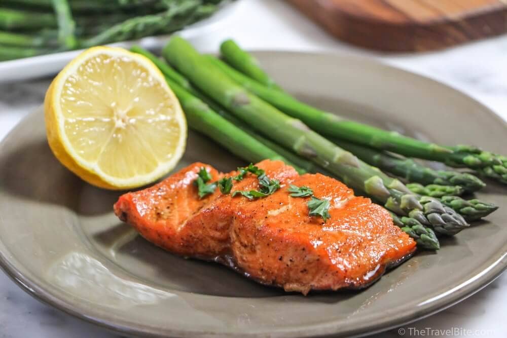 Maple Glazed Sockeye Salmon on a grey plate with lemon and asparagus.