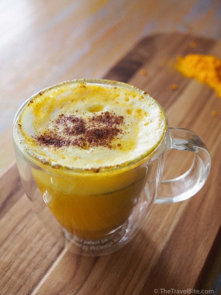Turmeric Milk Latte with layers of spice, orange turmeric milk, and froth with cinnamon.