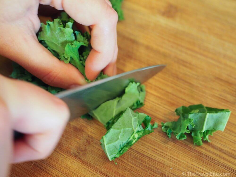 Cutting kale on wood cutting board. 