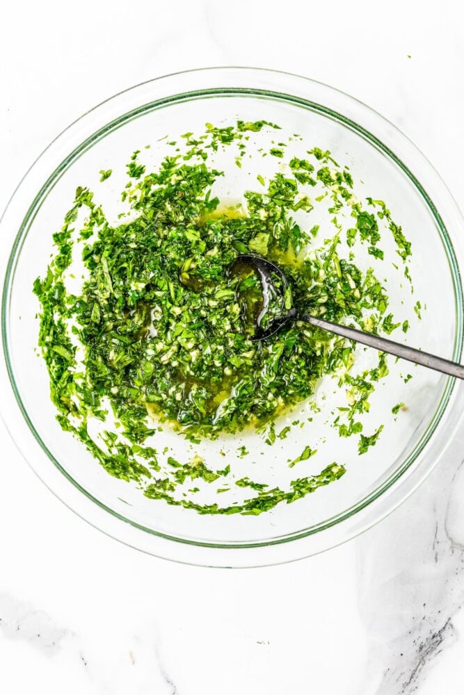 Chimichurri sauce in a clear glass bowl.