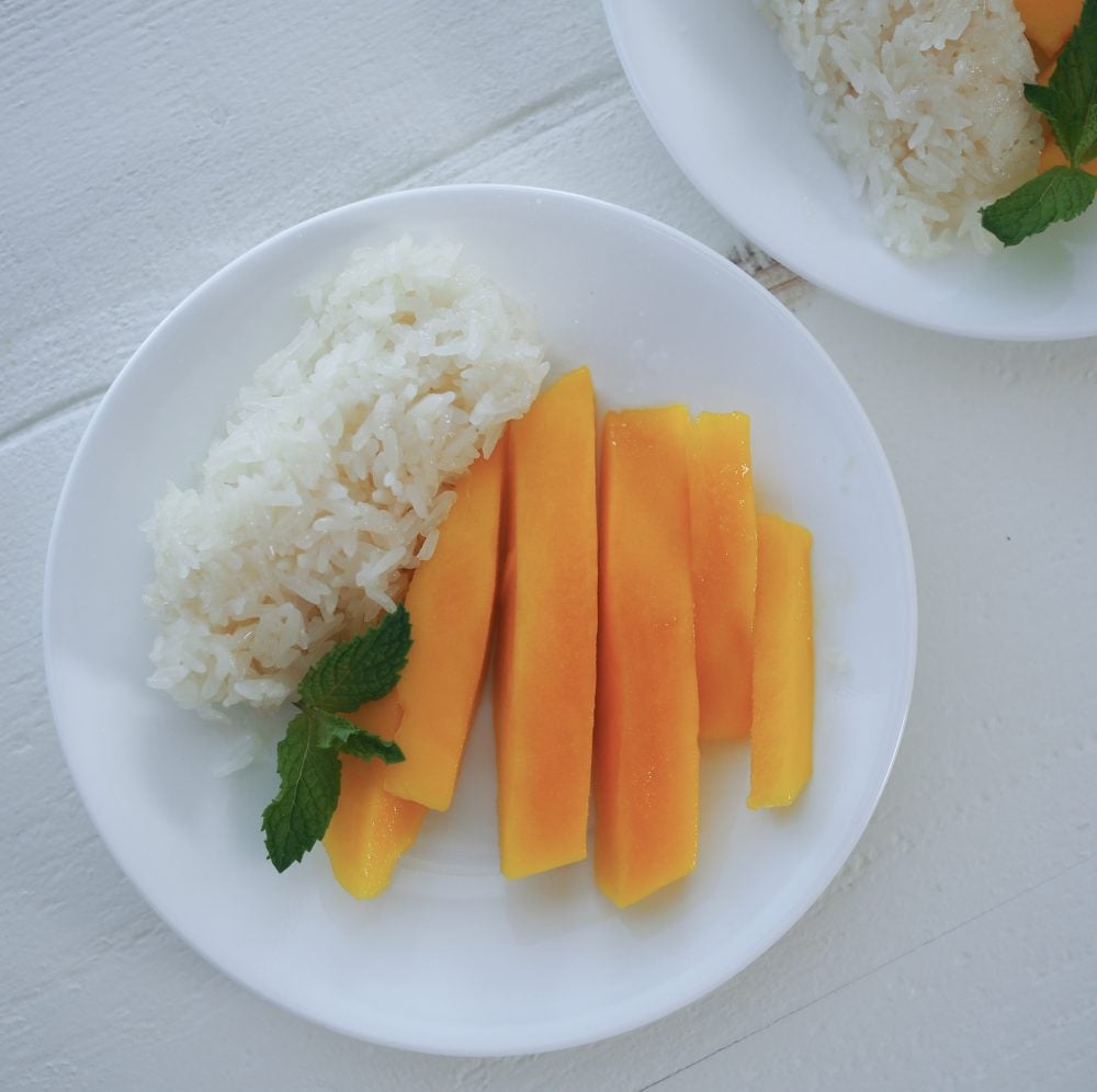 Sticky rice and mango with mint on a plate.