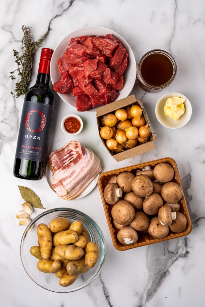 Ingredients for Beef Bourguigon: beef, red wine, tomato paste, thyme, bacon, fingerling potatoes, butter, beef stock, mushrooms, boiler onions, garlic, and bay leaf.