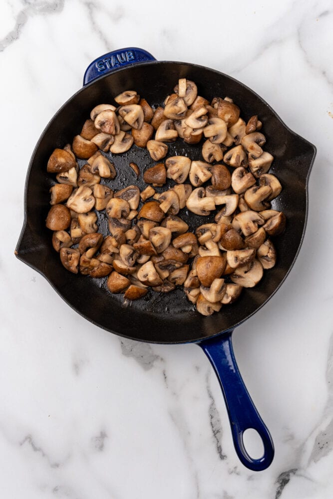cooked mushrooms in a blue Staub skillet